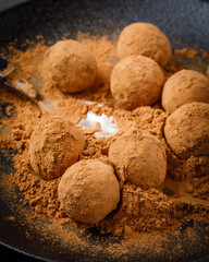 chocolate truffles or energy protein balls made with dry dates, walnuts, raisins, covered by cocoa powder