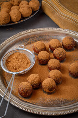 chocolate truffles or energy protein balls made with dry dates, walnuts, raisins, covered by cocoa powder