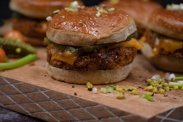 Vegan burgers made with seitan and vegan cheese, pickles on wooden cutting board