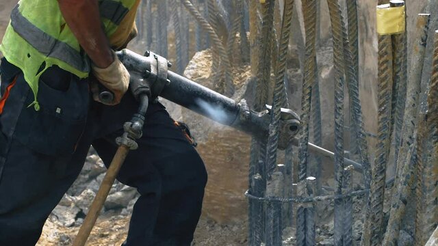 Slow motion shot of unrecognizable contruction site worker using pneumatic drill.