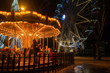 Fototapeta premium Fonte Nova's garden with Christmas market and colored ferris wheel near Ria de Aveiro at night