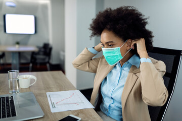 African American businesswoman using face mask while working in the office during coronavirus pandemic.