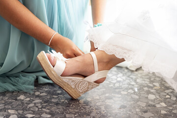 Closeup of the bridesmaid helping the bride with her elegant high heel