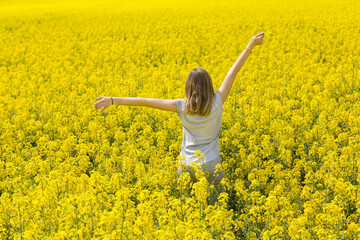 Young girl enjoy summer vacation in the middle of a yellow flowery field