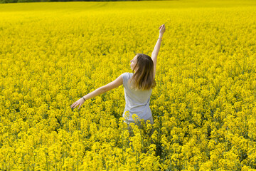 Young girl enjoy summer vacation in the middle of a yellow flowery field