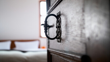 Old wooden brown door with iron mountings. Door wide open with a view on the hotel bed