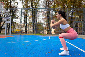 Athletic girl doing squats with resistance bands