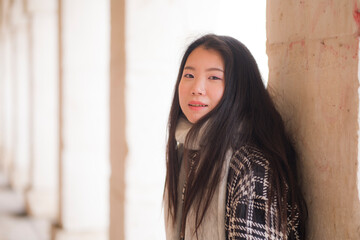 Fototapeta premium lifestyle portrait of young and beautiful Asian Chinese tourist woman smiling happy enjoying city tour walking around historic district on a sunny winter day in holidays travel