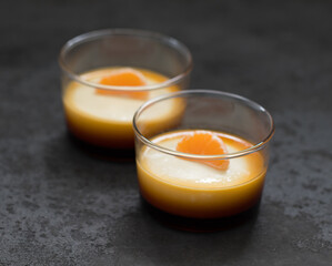 Cream caramel pudding with tangerine in a glass Cup on a dark background