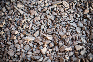 Gravel texture. Small stones, little rocks, pebbles in many shades of grey, white, brown, colour. Background of small wet stones in oval shape. Texture of little rocks from river or lake.