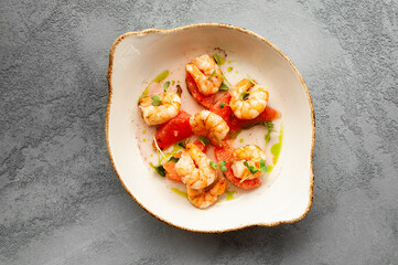 delicious prawns with grapefruit in a creamy sauce with herbs on a white plate, top view