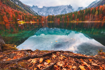 Lago di Fusine mountain lake in autumn colors and Mangart mountain in the background at sunset
