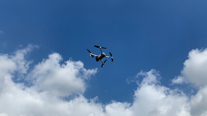 Latest technology RC camera drone or UAV (unmanned aerial vehicle) hovering on deep blue cloudy sky