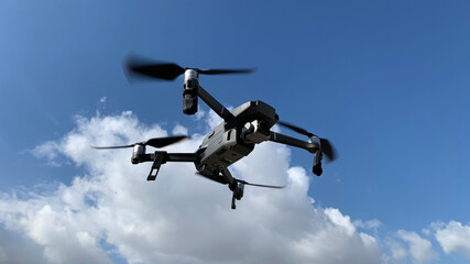 Latest technology RC camera drone or UAV (unmanned aerial vehicle) hovering on deep blue cloudy sky