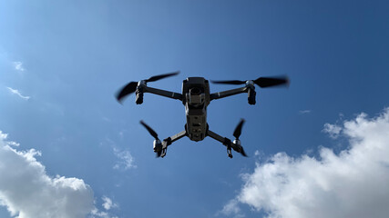 Latest technology RC camera drone or UAV (unmanned aerial vehicle) hovering on deep blue cloudy sky