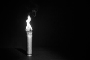 War candle. The candle burns in an empty sleeve. As a symbol of war and victims. Candle for remembering day. Located on black background. A candle used by the soldiers of the Second World War