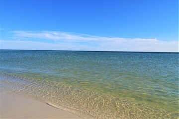 The seascape, a beautiful blank view from the coast of the Gulf of Mexico, calm ocean waters without waves over the horizon converge with a clear blue sky, in the foreground you can see the coast with