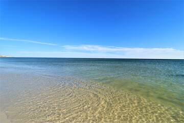 The seascape, a beautiful blank view from the coast of the Gulf of Mexico, calm ocean waters without waves over the horizon converge with a clear blue sky, in the foreground you can see the coast with