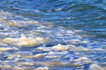 Small wave on the ocean shore, foam forms on the wave, close-up shot