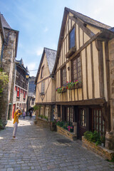 Fototapeta premium Dinan, France - August 26, 2019: View of historic colombage half-timbered and stone houses on the old cobblestoned street of Dinan, French Brittany