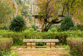 Fototapeta na wymiar Banco de pedra num jardim romântico