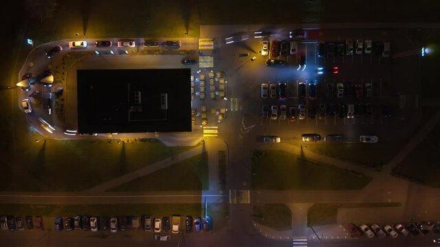 Queue of cars in a fast food restaurant. Busy Cafe drive at night. Aerial top down view. Hyperlapse. Parking cars at night. Time lapse. Light traces of headlights and side lights