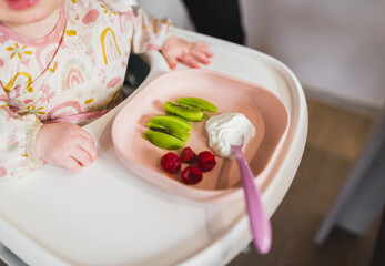 Obraz na płótnie Canvas baby eating raspberries, kiwi BLW meal 