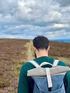 man in a field walking with a blue and grey backpack