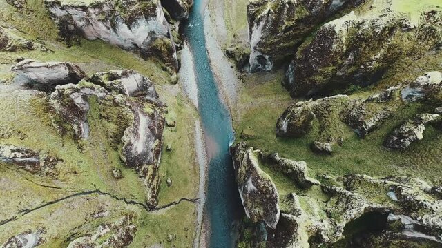 Slow drone shot looking down from above at Fjaðrárgljúfur canyon and river in Iceland