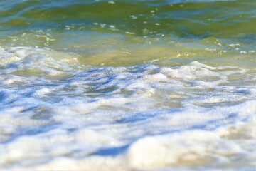 Small wave on the ocean shore, foam forms on the wave, close-up shot