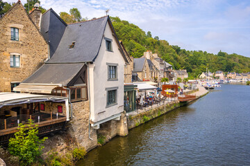Fototapeta na wymiar Dinan, France - August 26, 2019: Medieval stone houses with cafes and restaurants in the Dinan Port on the Rance River, French Brittany