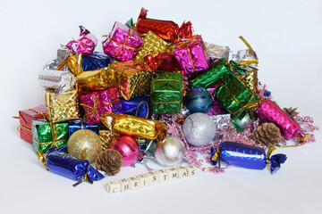 A large pile of New Year's gifts, sweets and toys lies on a white background next to the inscription Long-awaited winter holiday.  Celebrating at home.