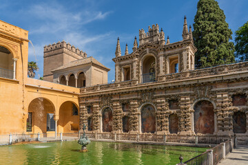 The Fountain with the historical building with painting in the yard of the Real Alcazar Palaces in Seville