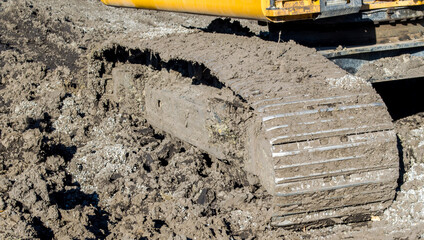 a filthy metal bulldozer track stuck in the mud © LI Cook