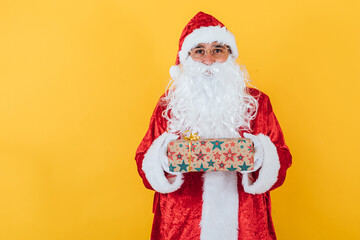 Santa Claus hold a gift on yellow background. Christmas concept