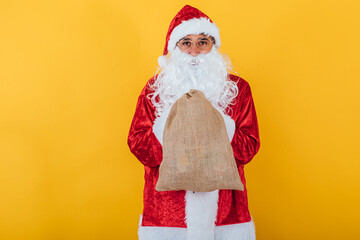 Santa Claus holding sack yellow background. Christmas concept
