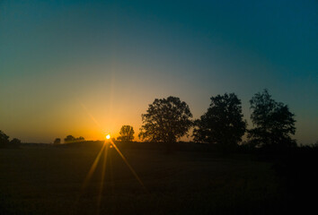 Naklejka na ściany i meble Rising sun over dark horizon seen by star filter