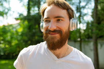 Relaxing, jogging with a music, outdoor on a sunny day. Smiling man listening to the music on a headphones. 