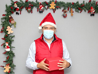 latin man with protection mask and gift box in christmas decoration, new normal covid-19