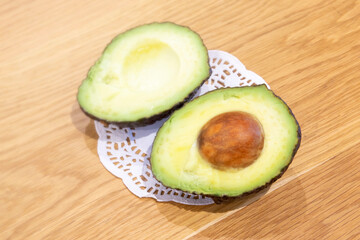 a halved avocado pear on a doily on a wooden table