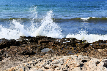 Beautiful bursts of foam waves on the seashore. White foam and bubbles beat against the rocky beach. Turquoise waves.