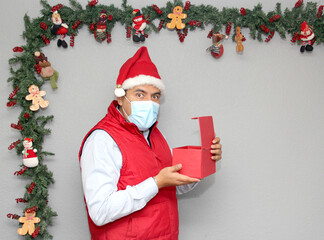 latin man with protection mask and gift box in christmas decoration, new normal covid-19