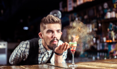 Portrait of bartender creates a cocktail in the pub