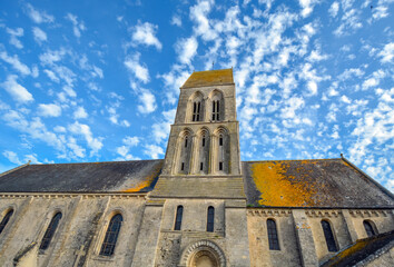 Fototapeta na wymiar L'eglise Saint-Martin in Formigny, Normandy, France, an important church in the D-Day invasion, showing the tower, blue sky and pigeons roosting.
