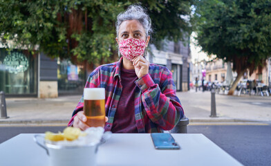 Caucasian female sitting in a cafe with a medical mask due to Covid-19 - the new normal concept