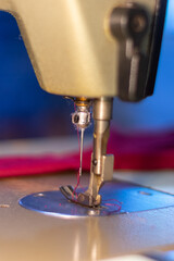 Vertical closeup shot of the needle of a sewing machine