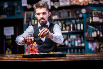 Portrait of bartender makes a show creating a cocktail in the pub