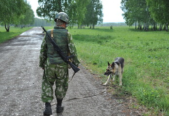 JURGA, SIBERIA, RUSSIA - JUNE 6,2011:Military dog handler with a Sheepdog to search for explosives