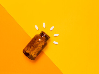 White medical pills and tablets spilling out of a amber glass bottle. Medicine creative concepts....