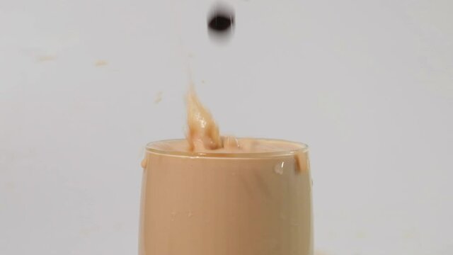 A slow motion footage of tapioca ball or pearl drop in milk tea. Pearl milk tea is famous drink in all country.